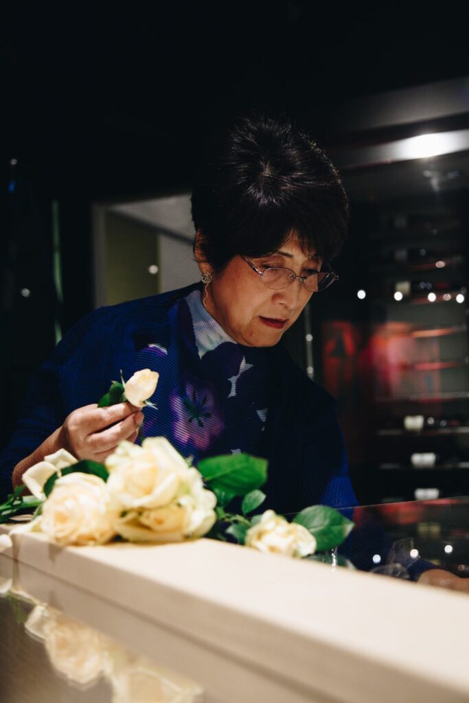 Carole Sakata working on a floral arrangement in a dimly lit setting