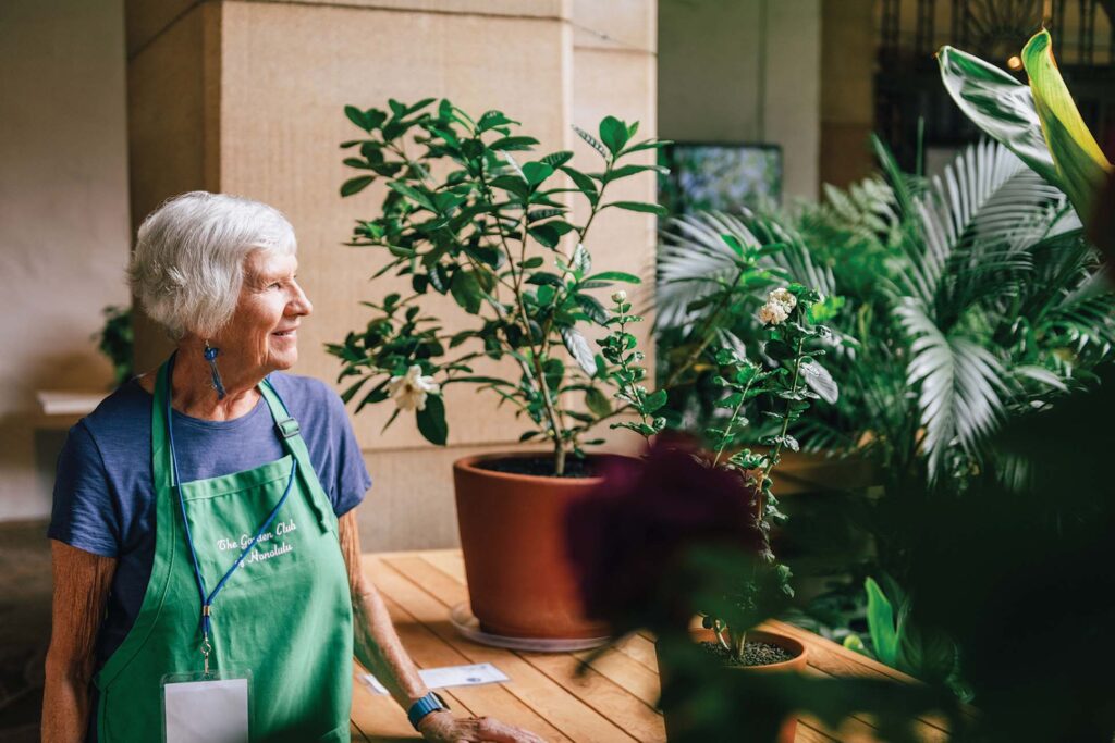 a person in an apron standing next to a potted plant