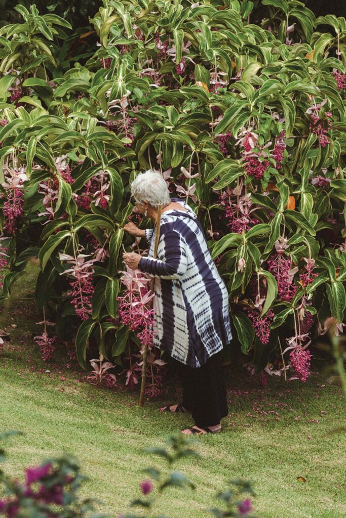 a person standing in front of a bush of flowers