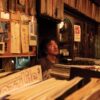a person sitting in front of a shelf with records