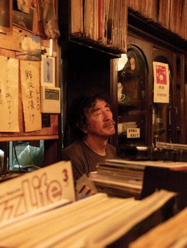 a person sitting in front of a shelf with records