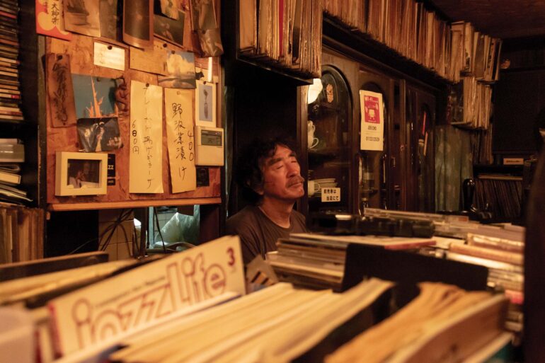 a person sitting in front of a shelf with records